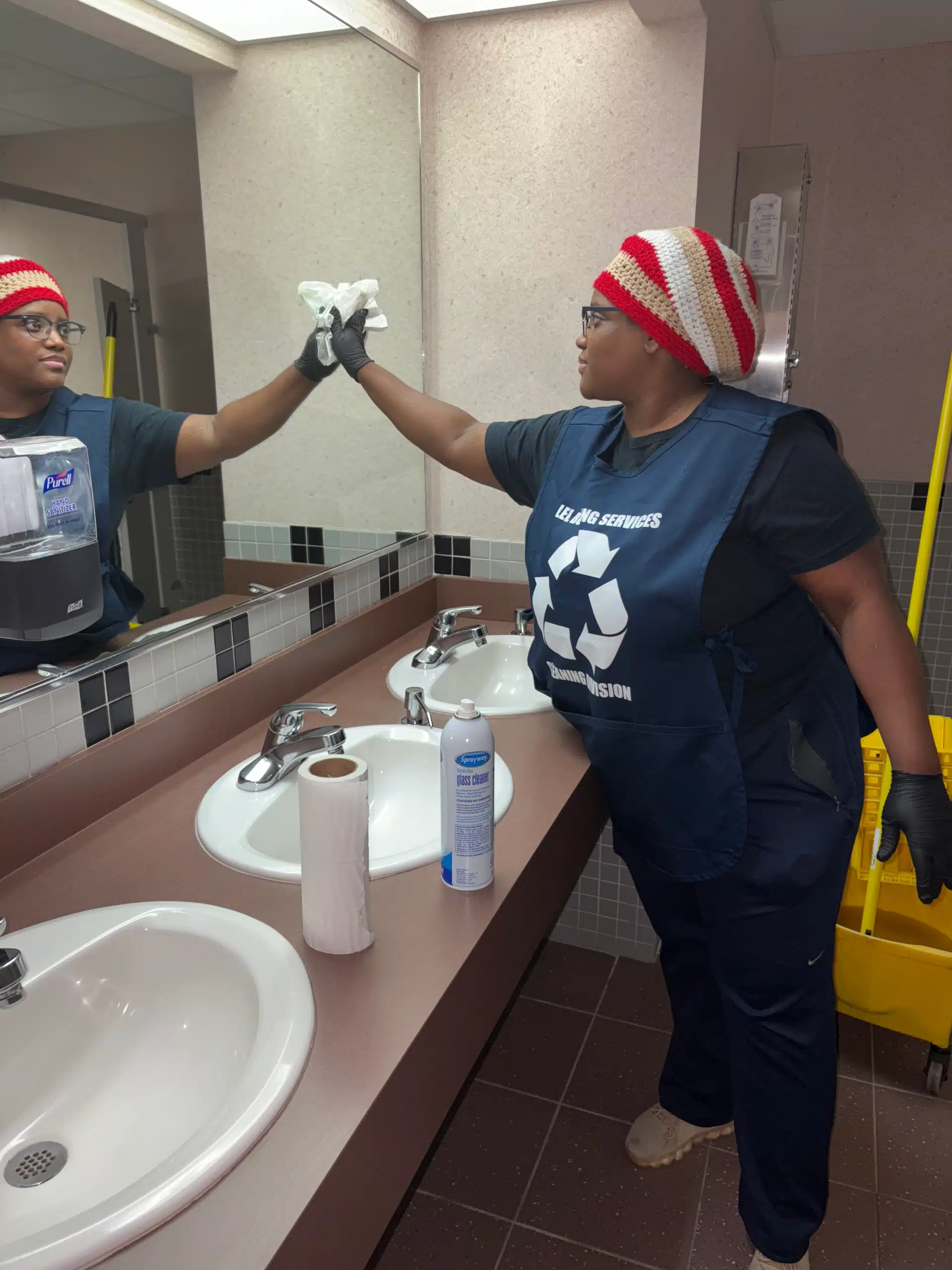 Woman cleaning bathroom mirror